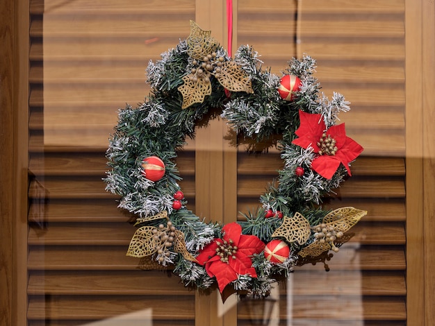 Guirnalda de Navidad con flores flor de Pascua en la puerta de cristal