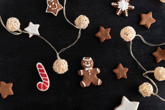 Guirnalda de Navidad y vista superior de galletas pintadas esmaltadas sobre fondo negro.