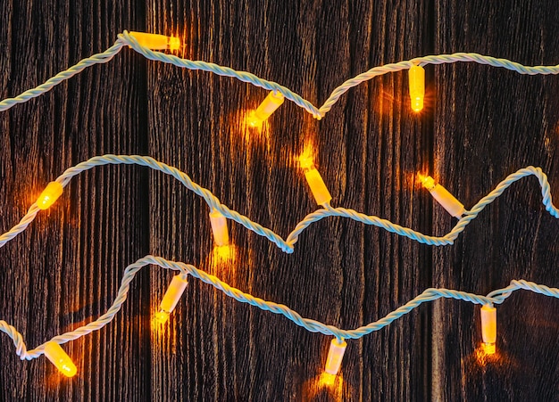 Foto guirnalda navideña con led amarillo y cable blanco sobre tablero de madera oscura