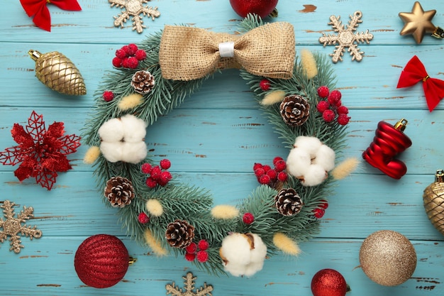 Guirnalda de ramitas de abeto, pino y abeto, decorada con algodón, flores y decoración navideña sobre fondo de madera azul. Vista superior