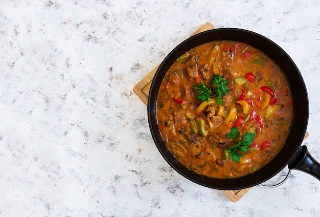 Guisado con carne y verduras en salsa de tomate en blanco. Vista superior