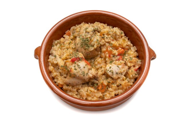 Guisado de arroz de frango servido em uma tigela de barro isolada no conceito de comida espanhola de fundo branco