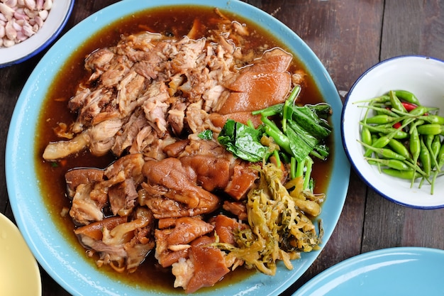 Guisado tailandés delicioso de la pierna del cerdo del estilo en la tabla de madera. Vista superior.