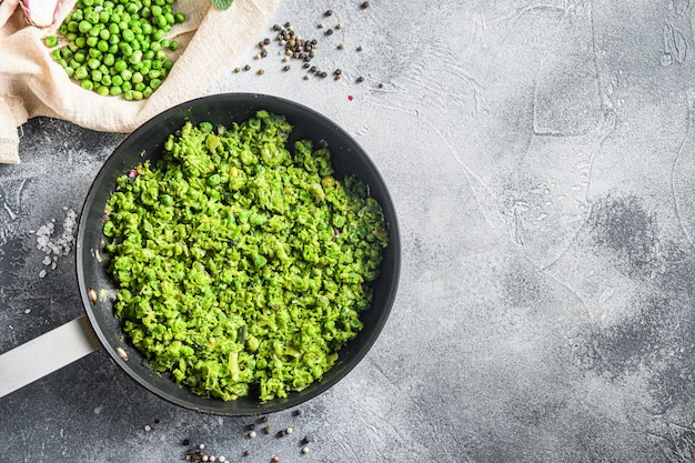 Guisantes blandos británicos cocidos sartén y guisantes en un tazón con chalota de menta, pimienta y sal sobre la superficie de piedra gris Ceto orgánico espacio de fotografía aérea para texto