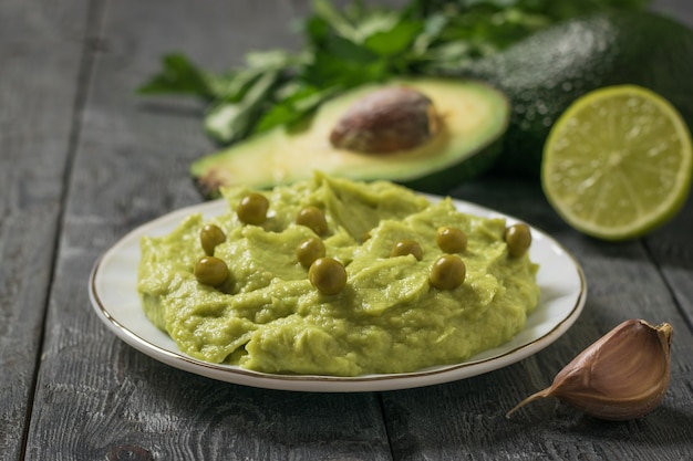 Guisantes en un cuenco de guacamole sobre una mesa de madera. Dieta vegetariana comida mexicana aguacate. Alimentos crudos.