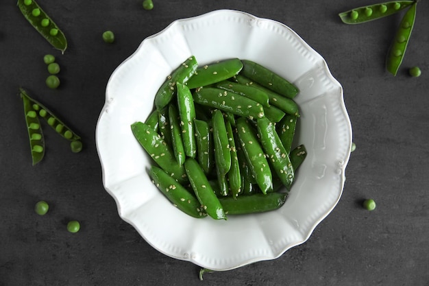 Guisantes frescos en un plato blanco sobre un fondo gris