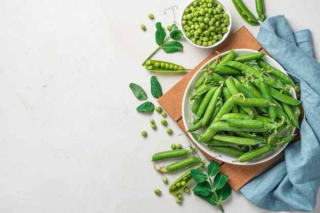 Guisantes jóvenes naturales y saludables sobre un fondo gris con espacio para copiar. Vista superior.