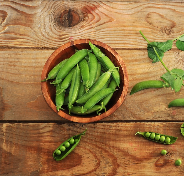 Guisantes jóvenes en un plato de madera