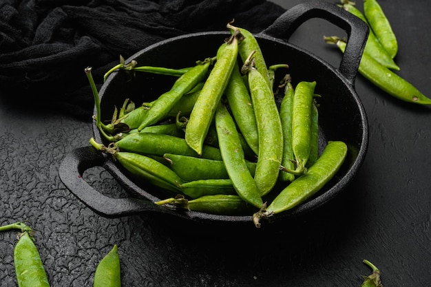 Guisantes de nieve orgánicos verdes crudos sobre fondo de mesa de piedra oscura negra