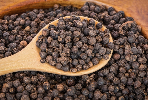 Guisantes pimienta negra en una cuchara de madera