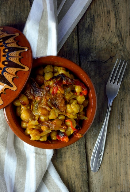 Foto guisantes con pimientos horneados en una olla de arcilla en una mesa de madera