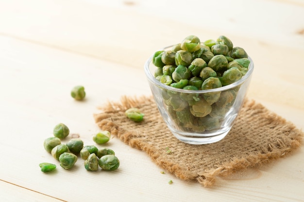 Guisantes salados en recipiente de vidrio en la mesa de madera