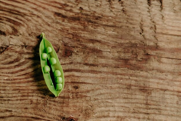 Guisantes tiernos sobre un fondo de madera. la vista desde la cima. refrigerio saludable. Comida vegana. guisantes abiertos