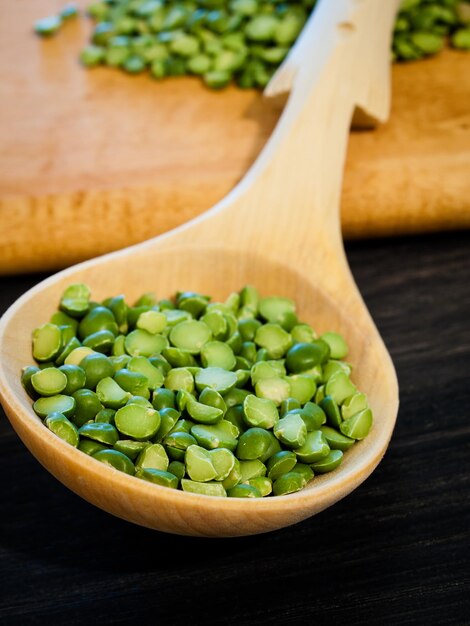 Guisantes verdes en cuchara de madera.