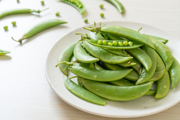 Guisantes verdes dulces frescos en la placa blanca.