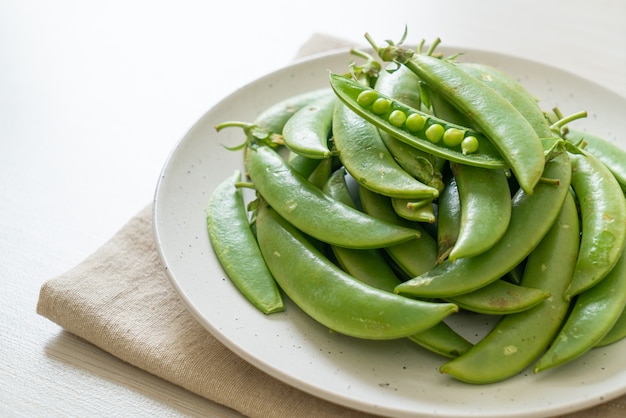 Guisantes verdes dulces frescos en la placa blanca.