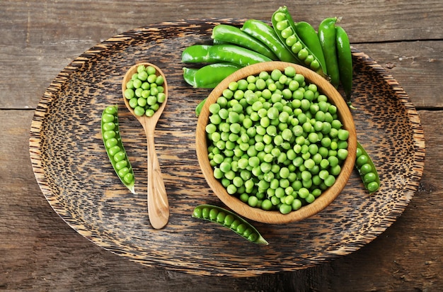 Guisantes verdes frescos en un cuenco en una bandeja de madera vista superior