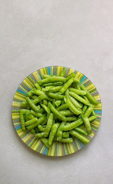 Guisantes verdes en un plato, gris