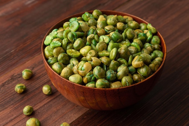 Guisantes verdes salados en cuenco de madera sobre la mesa, merienda saludable, comida vegetariana.