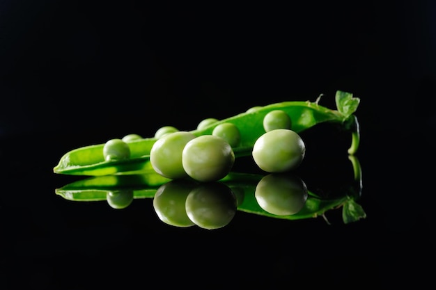 Guisantes verdes sobre un fondo negro closeupA vaina de guisantes verdes frescos