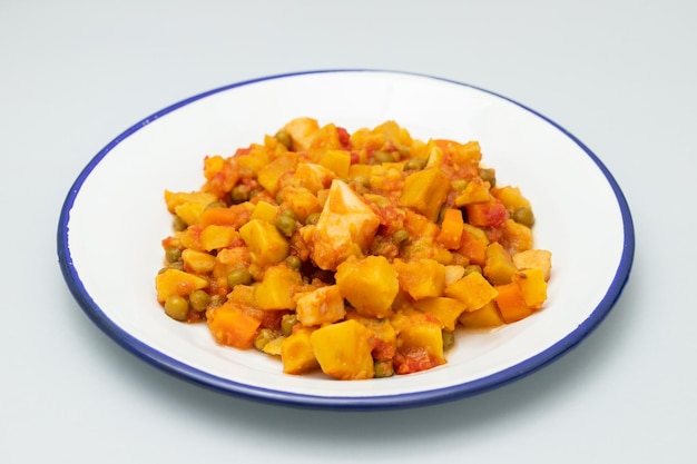 Guiso de calamares con verduras en plato blanco sobre gris