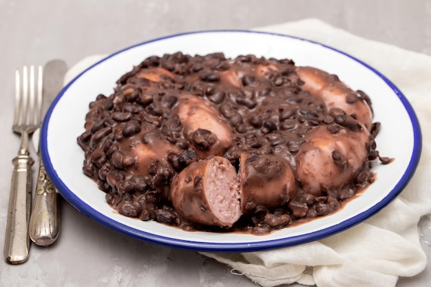 Guiso de frijoles negros con salchichas en un plato blanco