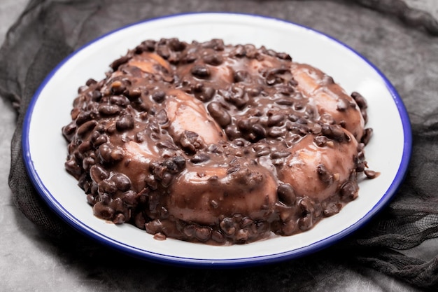 Guiso de frijoles negros con salchichas en un plato blanco