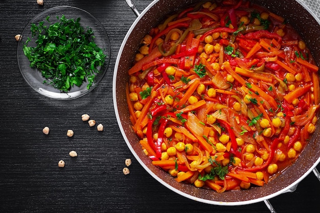 Guiso de verduras de garbanzos zanahoria pimientos cebollas ajo y salsa de tomate con limón en la mesa oscura Cocina oriental Vista superior