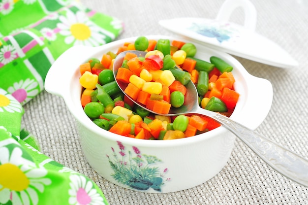 Guiso de verduras en una olla blanca sobre fondo de colores