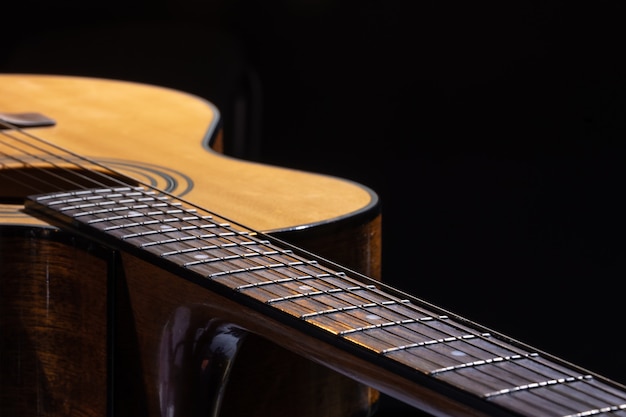 Guitarra acústica com uma bela madeira em um fundo preto.