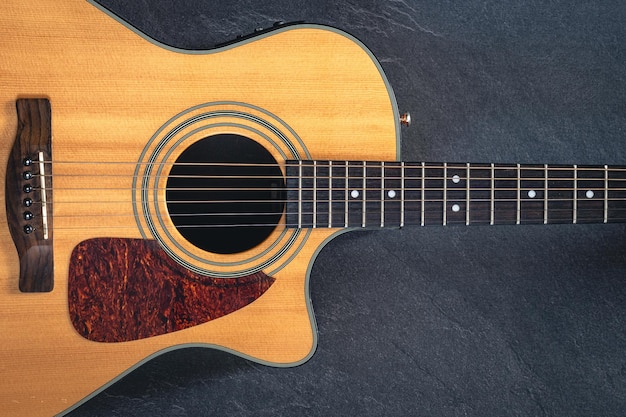 Guitarra acústica en un fondo de textura negra vista superior