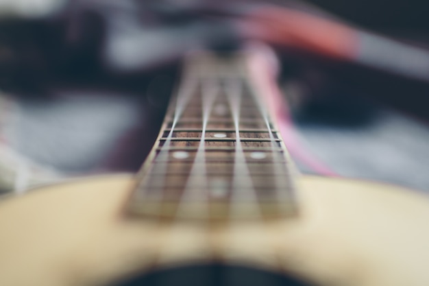Foto guitarra acústica de madera borrosa con cuatro cuerdas