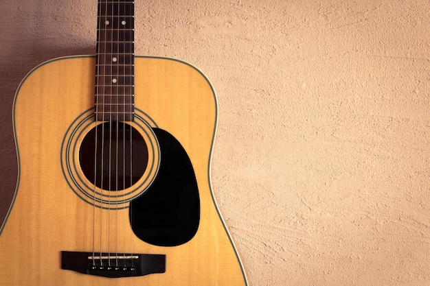 Foto guitarra acústica en la pared vintage de fondo beige