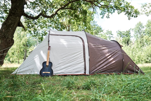 Guitarra acústica perto de uma barraca de acampamento em uma floresta