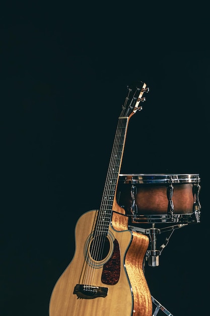 Guitarra acústica y tambor sobre un fondo negro aislado