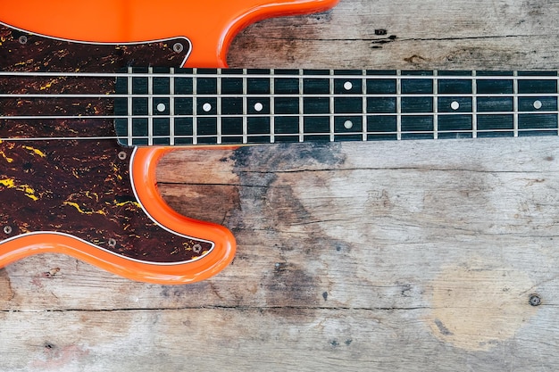 guitarra baixo elétrico laranja em fundo de madeira com espaço de cópia