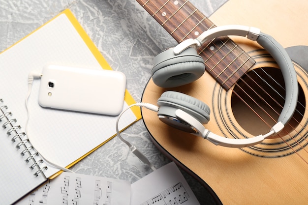 Guitarra clásica y auriculares con teléfono en superficie gris