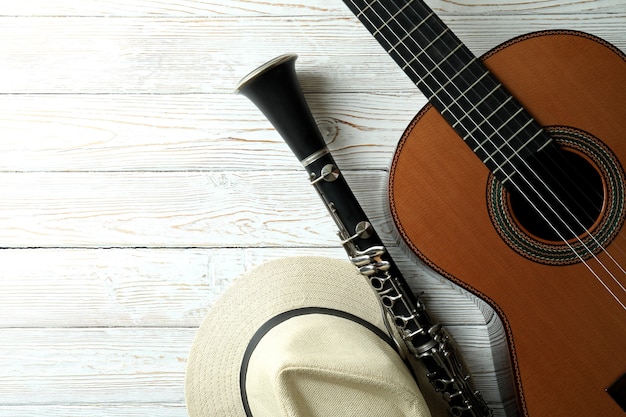 Guitarra clásica, clarinete y sombrero de mesa de madera blanca