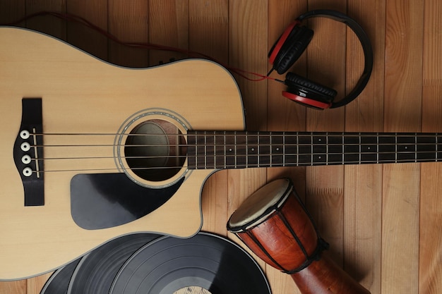 Guitarra com discos de vinil e tambor africano em mesa de madeira de perto
