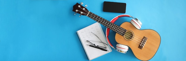 Guitarra com fones de ouvido, smartphones e notebooks em fundo azul