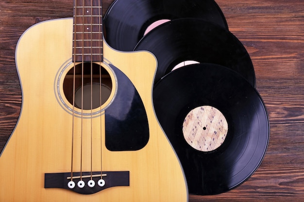 Guitarra y discos de vinilo en la mesa de madera de cerca