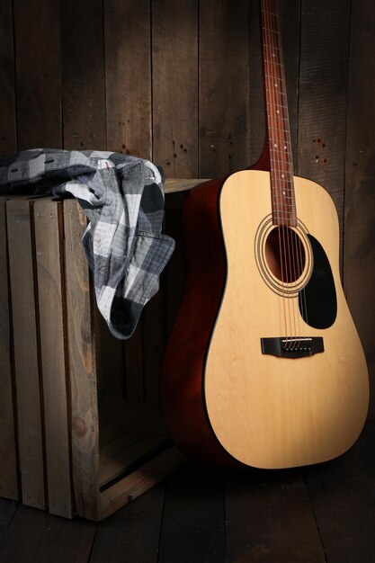 Foto guitarra e camisa deixadas na caixa no fundo da parede de madeira