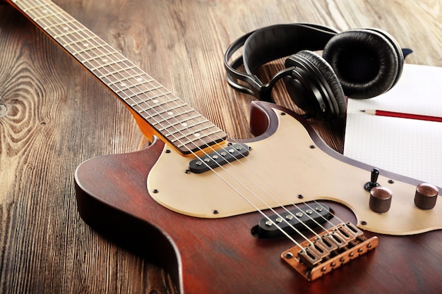 Guitarra eléctrica con auriculares y portátil en mesa de madera