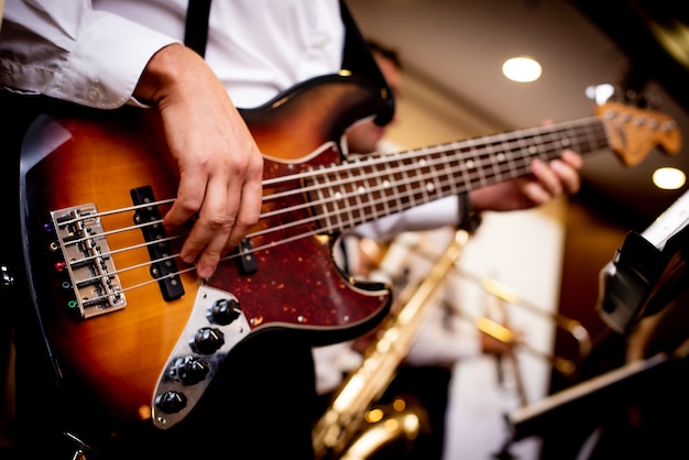 Guitarra electrónica en manos de un hombre vestido con una camisa blanca.