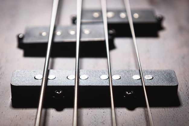 Guitarra elétrica baixa com quatro cordas fechadas detalhe do instrumento musical de rock popular visão aproximada do elemento do baixo texturizado de madeira