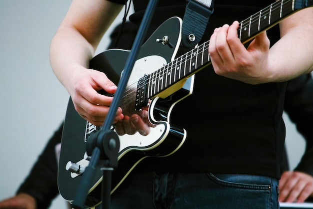 Guitarra elétrica cromada preta e mãos do guitarrista fechadas