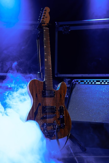 Foto guitarra elétrica de madeira com amplificador no palco com fumaça