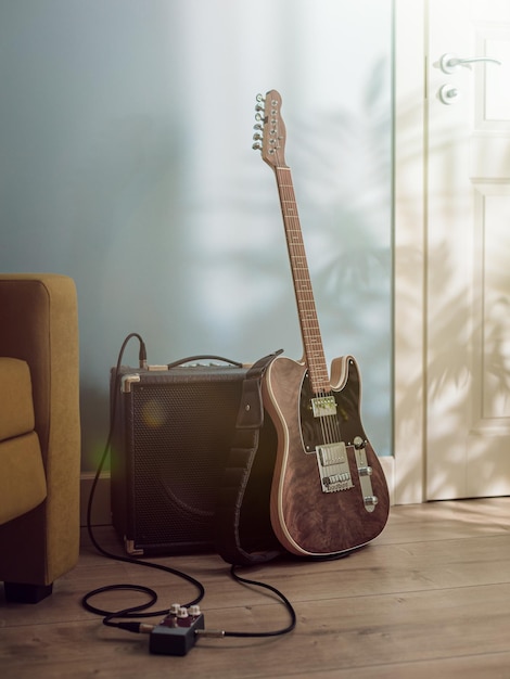 Guitarra elétrica e amplificador no chão da sala de estar sob a luz do sol da janela