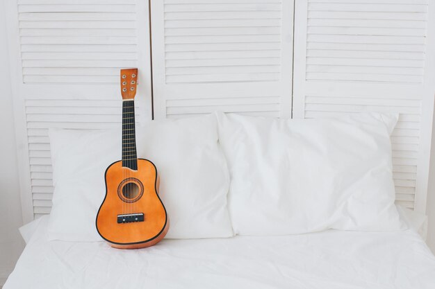 Guitarra encontra-se em uma cama branca. Composição romântica. Tonificação.