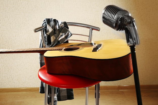 Foto guitarra no banquinho vermelho e microfone no estúdio fechado